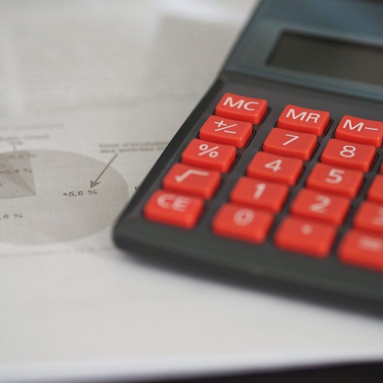 Calculatrice avec touches rouges et document avec graphique en arrière-plan.
